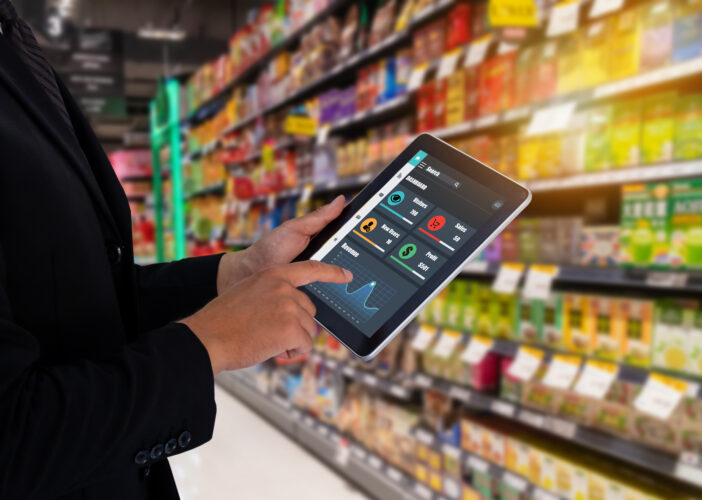 Retail employee uses tablet to monitor store network performance, showing metrics like sales and endpoint health