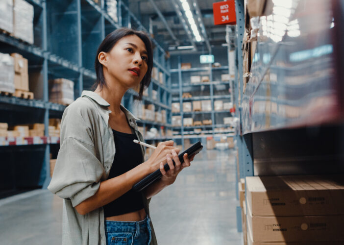 Retail employee using a tablet in a warehouse, reflecting how scalable network architecture supports growth into new operations.